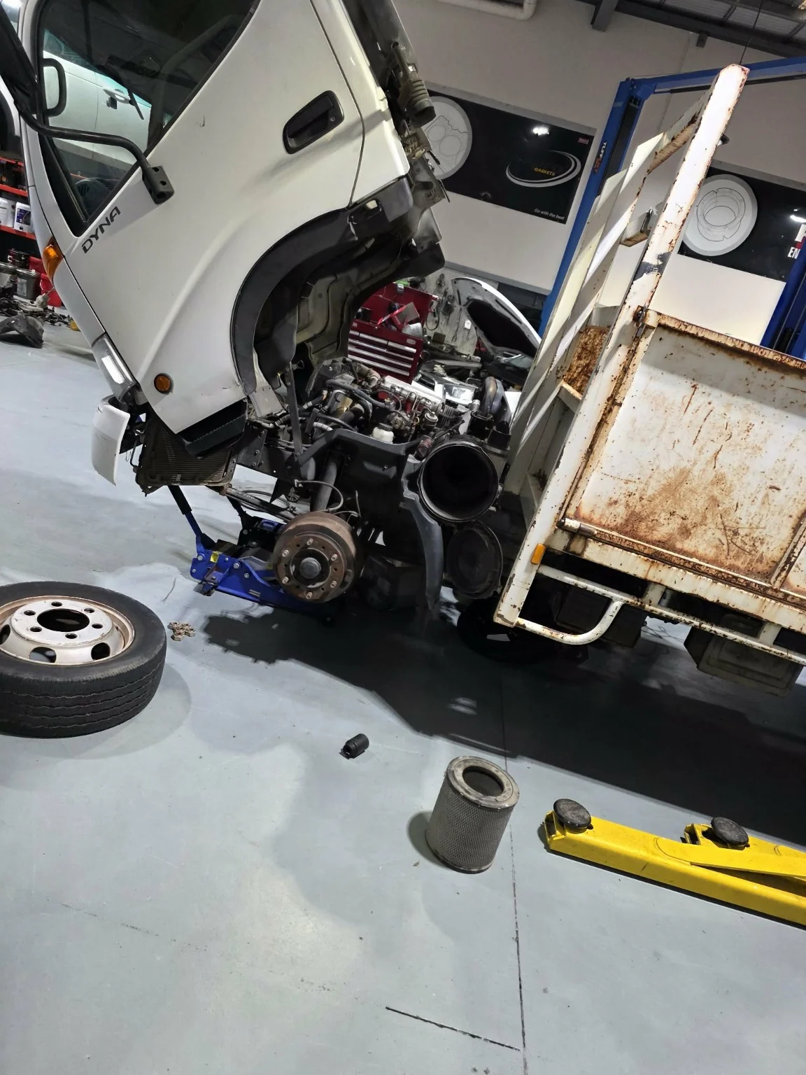 Toyota Dyna truck with its cab tilted forward and engine exposed in the Autotech workshop