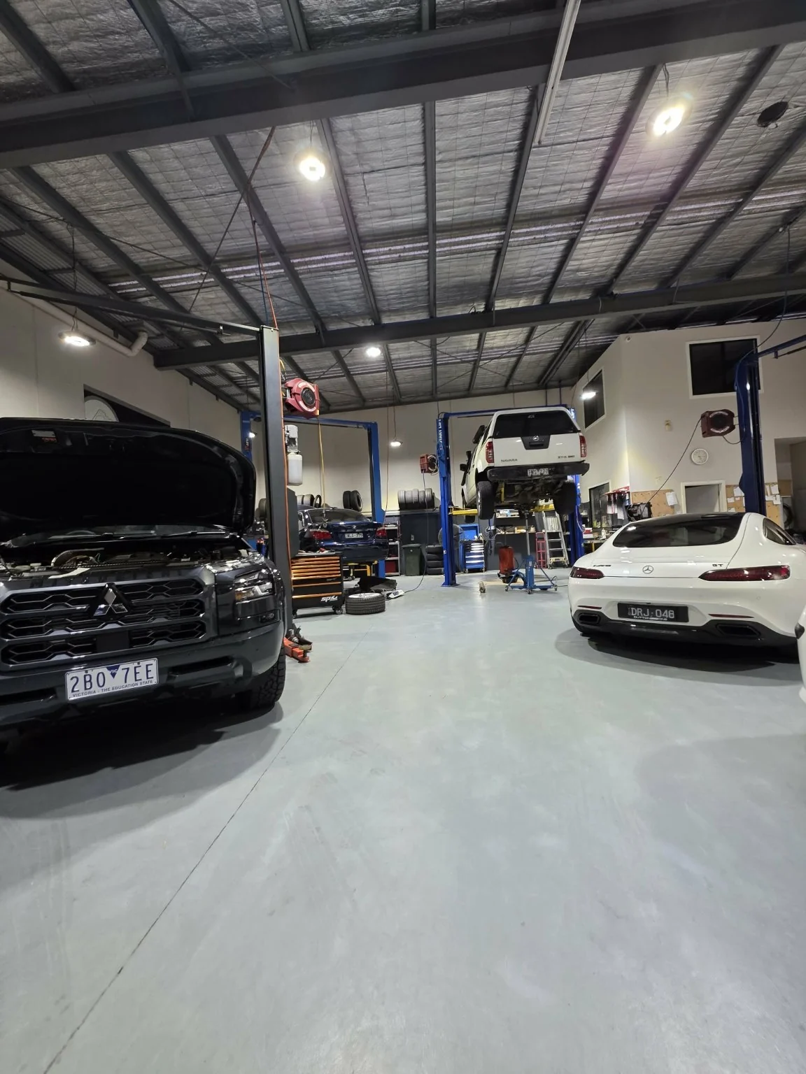 Mitsubishi ute, Mercedes coupe and a raised ute inside the Autotech workshop in Sunshine West